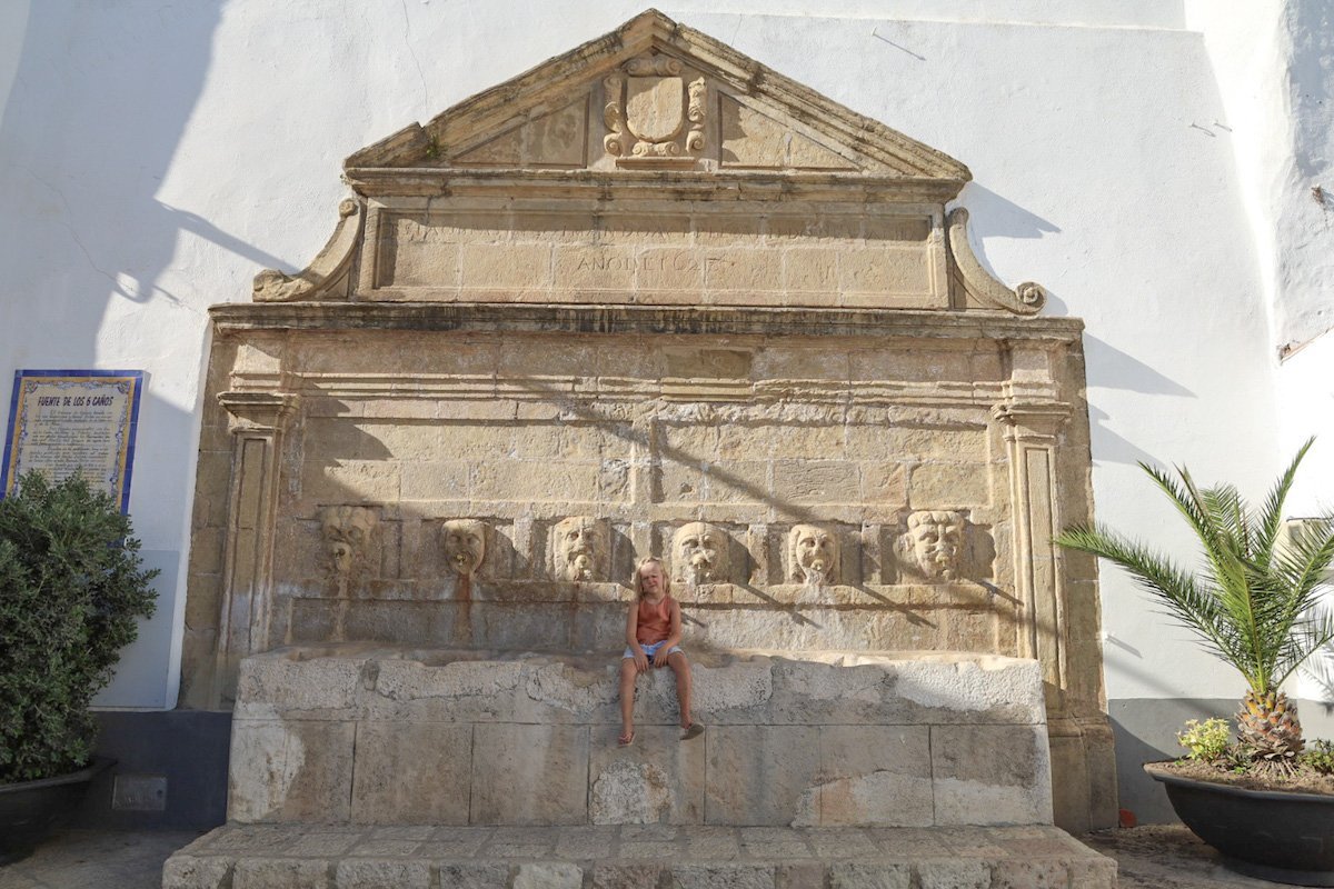 child sits at water fountain on a Southern Spain road trip itinerary